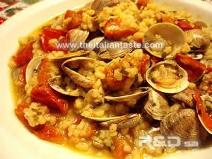 fregola whith clams, the molluscs are in their shells and tomatoes are fresh and cut into pieces