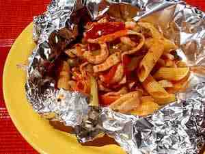 pasta with fish and vegetable sauce that is baked in the foil, the photo shows pasta dressed with the sauce in the foil