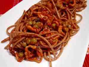 wholemeal spaghetti with squi-and-pea sauce, the photo shows a detail of a spaghetti platter and on top peas and squid pieces