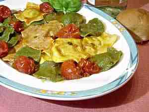coloured italian ravioli-the photo shows some yellow, red and green ravioli on a dish dressed with tomato sauce and some basil leaves