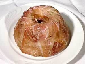 Rice timbale wrapped in ham slices in a white serving dish