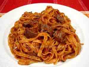 Fettuccine with chicken livers and wild mushrooms served on a white plate