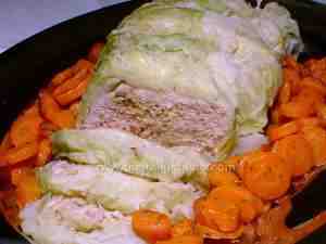 meat roll in savoy cabbage leaves, placed in a serving plate and surrounded by a carrot side dish