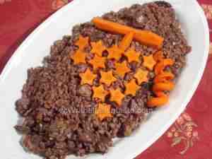 Christmas risotto made with chestnuts, mushrooms and salami and decorated with grape made with carrots