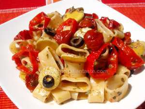 Pasta salad with ring-shaped ingredients, the photo shows calamarata pasta combined with bell pepper rings, black olive slices, courgette (zucchini) slices