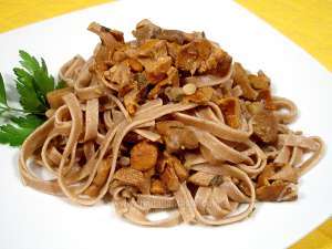 emmer tagliatelle with chanterelle mushroom and chestnuts, the photo shows a dish with tagliatelle and pieces of chestnuts and mushroom, garnished with a sprig of parsley