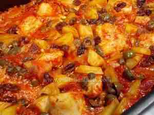 Cod in sauce, Sicilian recipe. The image shows cod pieces in tomato sauce enriched with green olives, capers, pini nuts, sultanas, potatoes