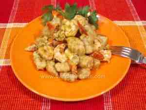 Potato gnocchi dressed with seafood sauce on orange serving platter