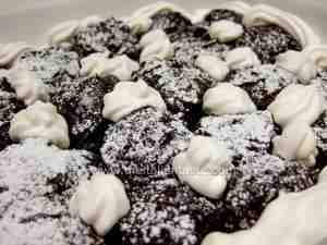 profiteroles layered in a serving platter, garnished with whipped cream and sprinkled with icing sugar