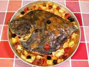 baked turbot in baking pan along with potatoes, olives and tomatoes